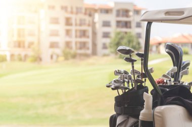 Golf sahasında golf arabası üzerinde golf kulüpleri seti 