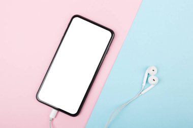 Akıllı telefon, mavi ve pembe arka planda kulaklıklı cep telefonu. Müzik dinlemeye hazır.