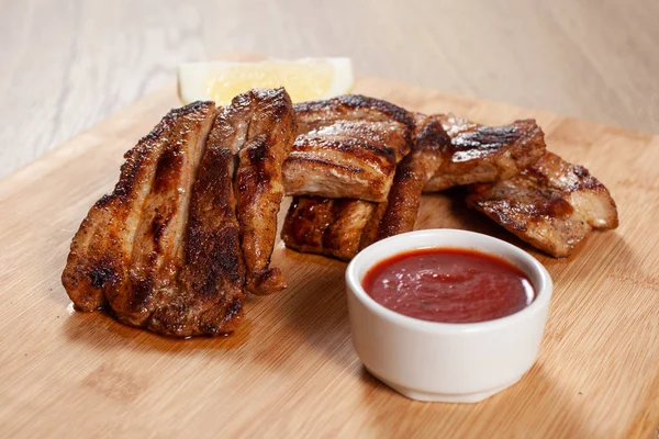 Deliziose costole alla griglia con salsa rossa su tavola di legno — Foto Stock