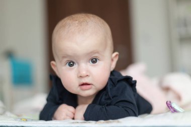 Midesinin üzerinde yatan sevimli bir bebeğin portresi. Aile sabahı evde. Karın zamanı