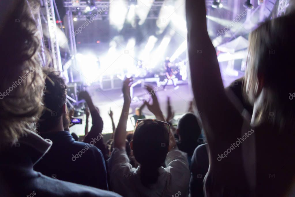 Silhouettes of concert crowd in front of stage lights. Fans during a life concert