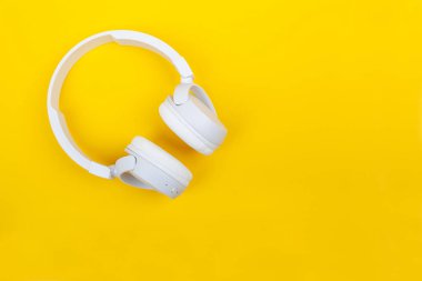 Sarı zemin üzerine beyaz kablosuz kulaklık. Müzik konsepti. Sarı arka plan üzerinde kulaklık. 