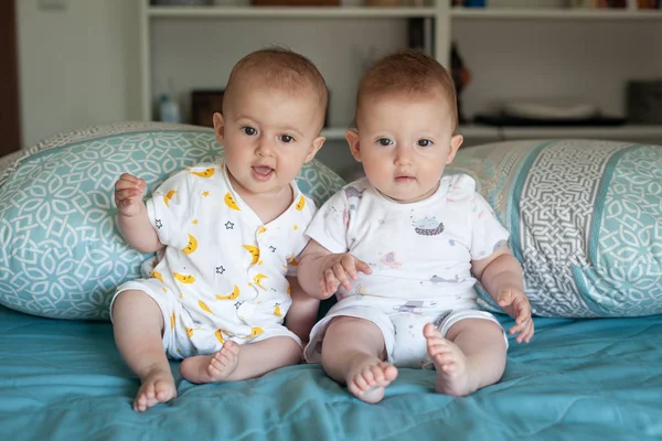 Hermanas gemelas felices con pijamas riendo en la cama en casa.. . — Foto de Stock