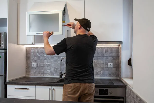 Marangoz yeni mutfakta çalışıyor. Tamirci mutfakta kapı tamir ediyor.