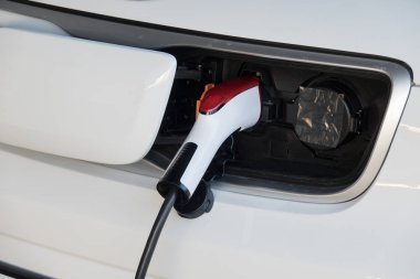 Elektrikli araba aküsünü şarj et. Şarj istasyonunda elektrik kablosu takılı elektrikli araba.