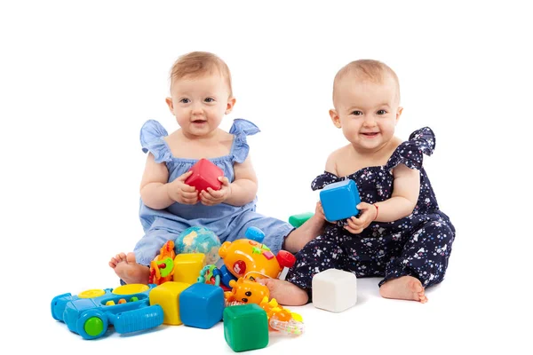 İki sevimli kız bebek oyuncaklar ile oynarken, beyaz izole — Stok fotoğraf