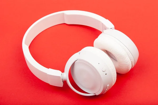 Casque blanc sans fil sur fond rouge. Concept musical. Écouteurs sur fond rouge. — Photo