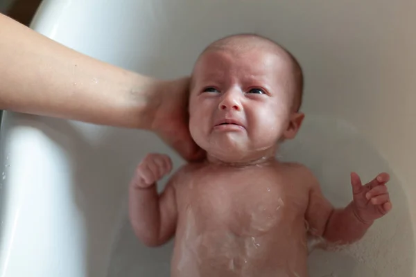 Newborn baby is being bathed by his mother. Newborn baby crying in bath time — Stock Photo, Image