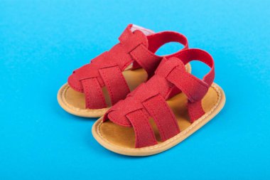 Mavi arka planda bir çift bebek sandaleti ayakkabısı