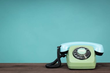 Eski telefon ahşap masada, yeşil arka planın önünde. Eski telefon