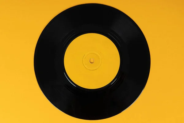 Old vinyl disc on yellow background. Old vintage vinyl record.