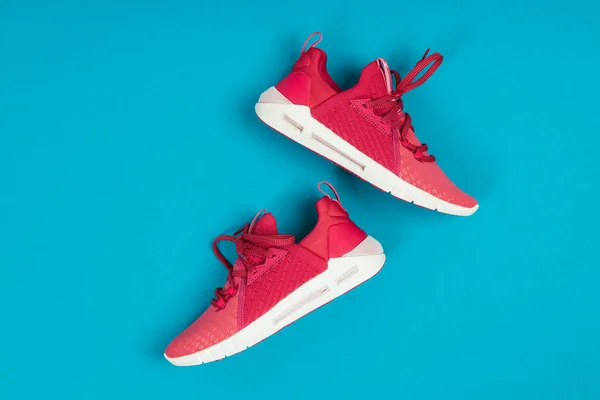 Pair of new pink sneakers, sport shoes on blue background. Pink womens sport, running shoes