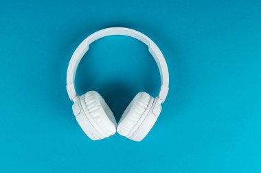 Mavi arka planda kablosuz beyaz kulaklık. Müzik konsepti. Mavi arka planda kulaklıklar. 