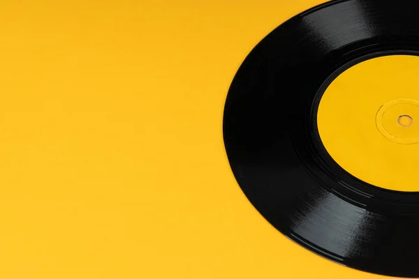 Old vinyl disc on yellow background. Old vintage vinyl record.