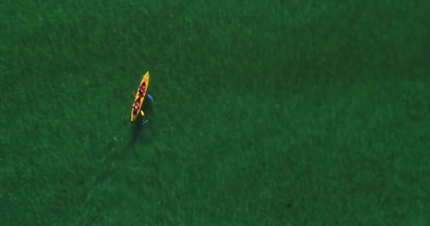 ターコイズブルーの澄んだ水に浮かぶ二重カヤックの空中ドローンショットのトップダウン — ストック動画