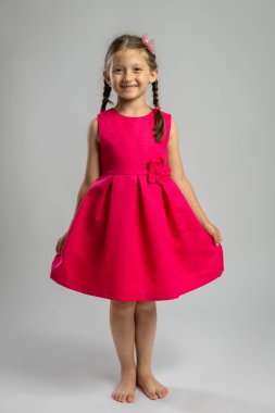 Parlak Pembe Elbiseli Gülümseyen Küçük Kız Saçlı Yalınayak Stüdyoda. Çocukluk Neşe, Moda Portresi, Masumiyet ve Yaşam Tarzı Oyunculuğu veya Çocuk Giyim Konsepti