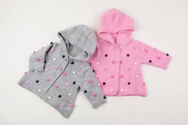 Şirin pembe ve gri örülmüş kapüşonlu ve ponlu bebek hırkaları. Çocukların kış modası