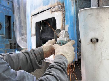 İşçi, metali köşeli öğütme makinesiyle kesiyor