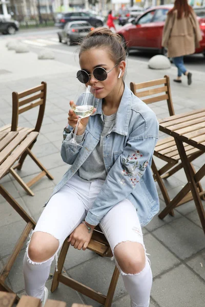 Hermosa chica bebe vino blanco en un café de la calle . —  Fotos de Stock