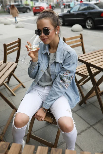 Hermosa chica bebe vino blanco en un café de la calle . —  Fotos de Stock