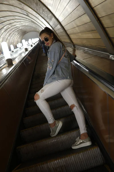 Back view. A stylish girl climbs up the escalator. — Stock Photo, Image