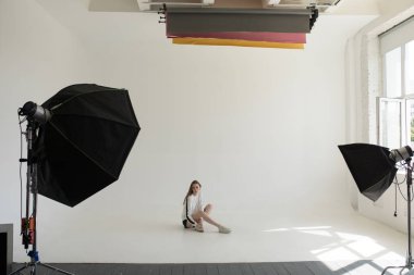 Model oturma ve profesyonel fotoğraf stüdyosu beyaz bir arka plan üzerinde poz.