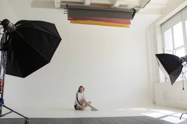 Model oturma ve profesyonel fotoğraf stüdyosu beyaz bir arka plan üzerinde poz.
