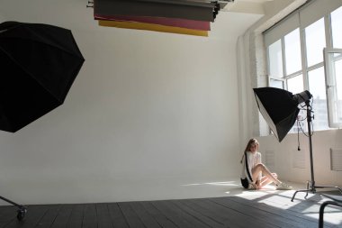 Model oturma ve profesyonel fotoğraf stüdyosu beyaz bir arka plan üzerinde poz.