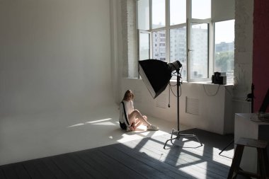 Model oturma ve profesyonel fotoğraf stüdyosu beyaz bir arka plan üzerinde poz.