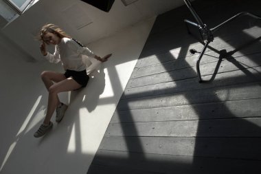 Profesyonel fotoğraf stüdyosu yerde modeli oturur.