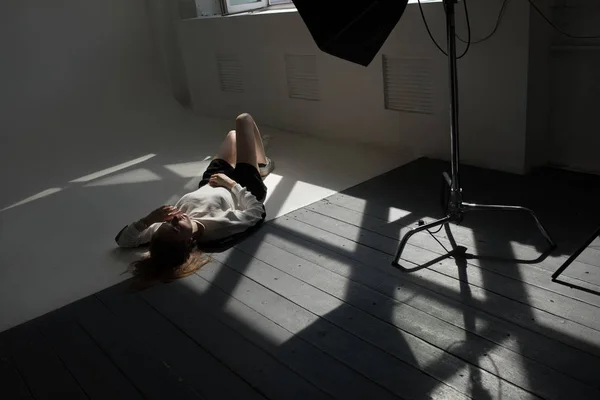 Modelo se encuentra en el suelo en un estudio de fotografía profesional . — Foto de Stock