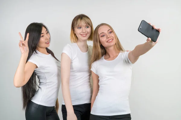 Красиві смішні дівчата роблять селфі. Дівчата в білих футболках . — стокове фото