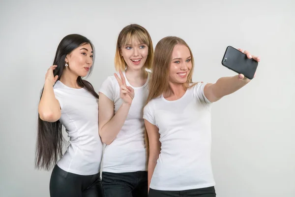 Όμορφη αστεία κορίτσια κάνουν selfie. Κορίτσια στα λευκά μπλουζάκια. — Φωτογραφία Αρχείου