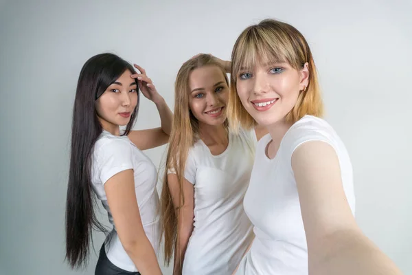 Hermosas chicas divertidas hacen selfie. Chicas en camisetas blancas . — Foto de Stock