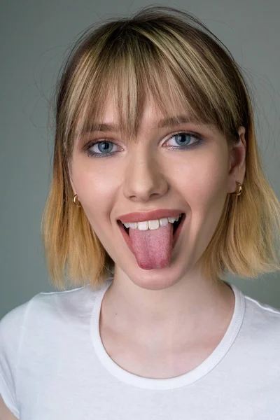 Retrato de uma menina bonita mostrando a língua . — Fotografia de Stock