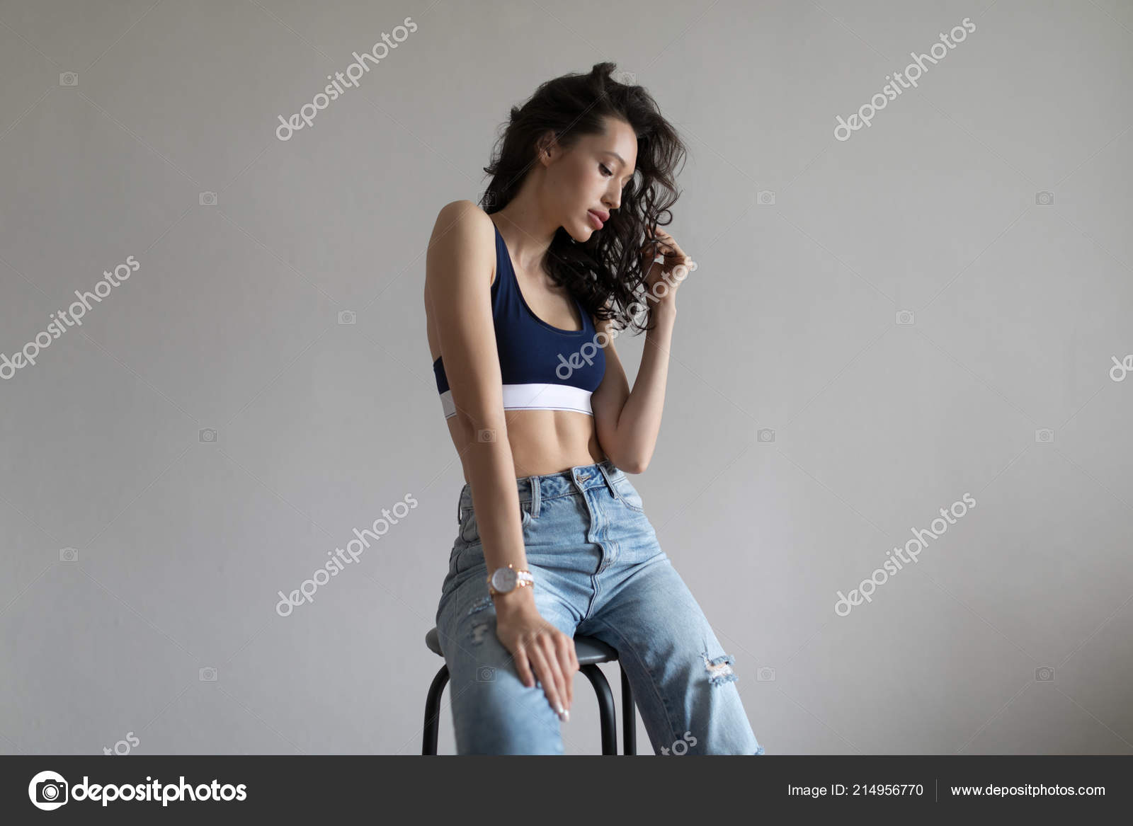 Attractive woman in sports top and jeans poses on white background. Stock  Photo by ©airkost 214956770