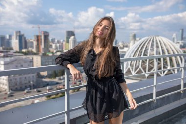 Young woman standing on the terrace overlooking the city. clipart
