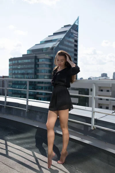 Jovem mulher de pé no terraço com vista para a cidade . — Fotografia de Stock