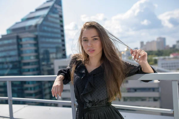 Junge Frau steht auf der Terrasse mit Blick auf die Stadt. — Stockfoto