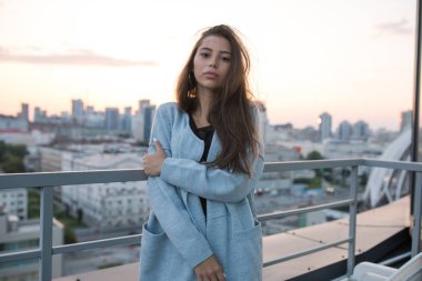 Çekici genç kadın şehir ve günbatımı karşı duruyor.
