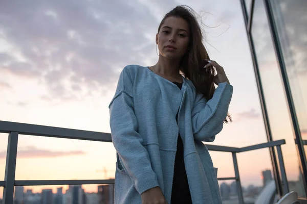 Attractive young woman stands against city and sunset. — Stock Photo, Image