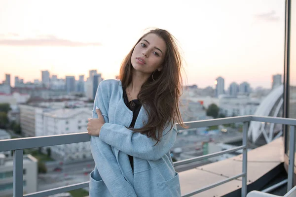 Jovem mulher atraente está contra a cidade eo pôr do sol . — Fotografia de Stock