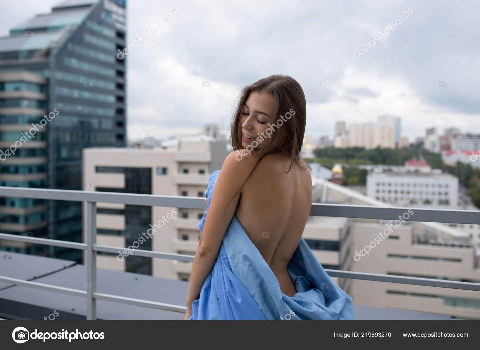 Chica desnuda envuelta en una manta se para en la terraza con vistas a la  ciudad .: fotografía de stock © airkost #219893270 | Depositphotos