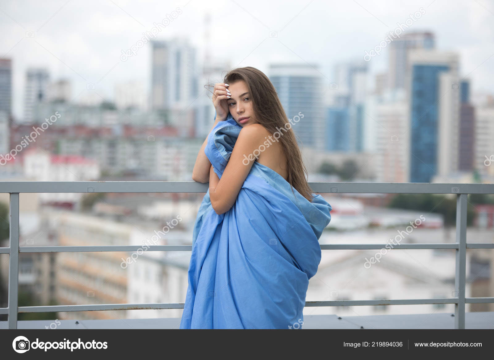Naked Girl Wrapped In A Blanket Stands On The Terrace Overlooking The
