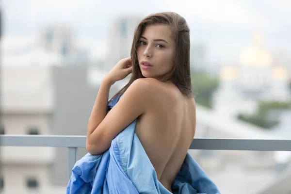 Ragazza nuda avvolta in una coperta si trova sulla terrazza con vista sulla città . — Foto Stock