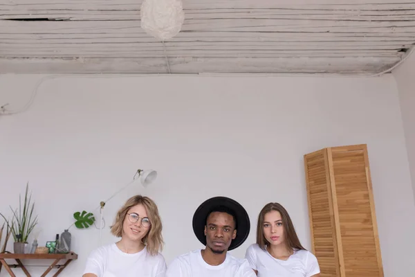 Grupo multirracial de amigos están sentados en la cama . — Foto de Stock