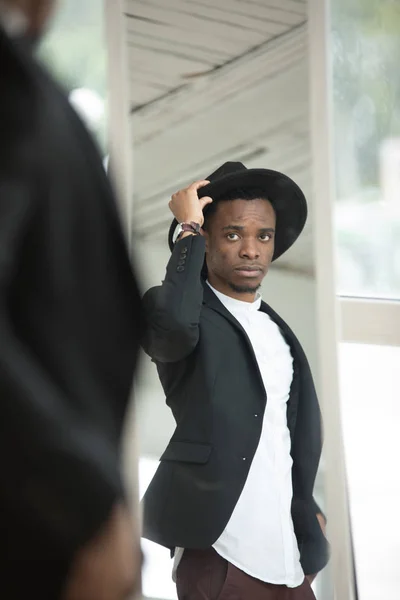 African American man in a hat looks in the mirror. Stock Picture