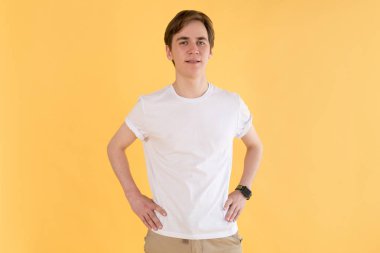 Beyaz bir t-shirt genç adam sarı bir arka plan üzerinde duruyor. Mock-up.
