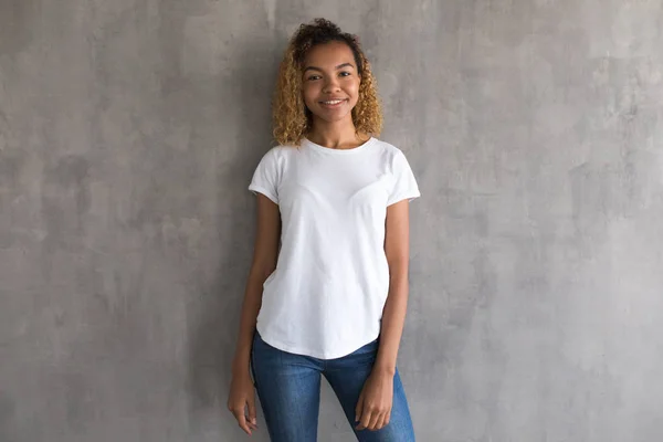 Hermosa chica en una camiseta blanca sobre un fondo gris. Mock-up . — Foto de Stock