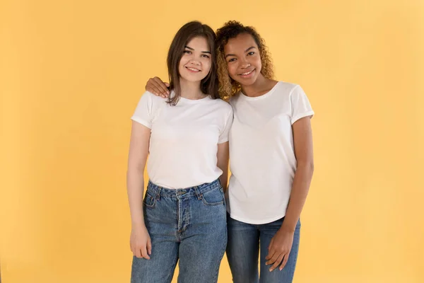 Multirassische Freunde in weißen T-Shirts auf gelbem Hintergrund. Attrappe. — Stockfoto